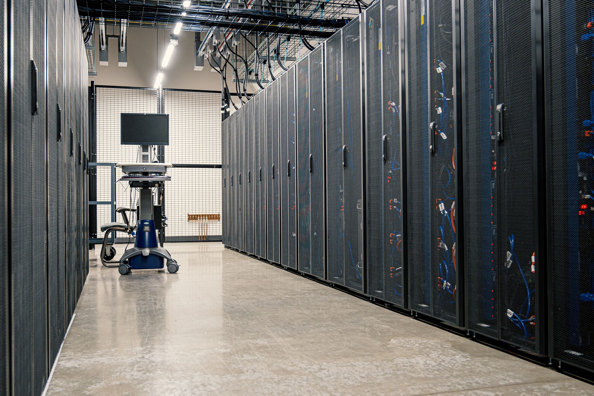 Data center aisle. Server racks and overhead cable.